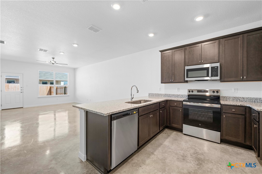 2819 Quail Rdg Lane Temple, TX 76501 - Photo 5 of 17 a kitchen with stainless steel appliances granite countertop a sink and a stove top oven with wooden floor