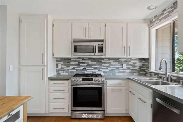 a kitchen with granite countertop a stove sink and cabinets