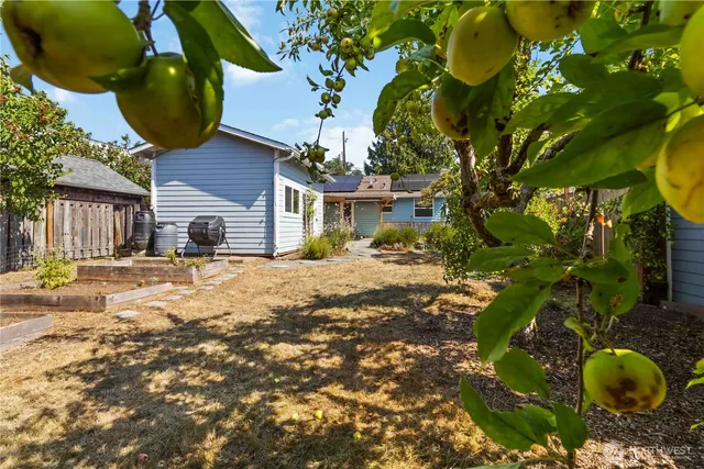 a backyard of a house with table and chairs under an umbrella