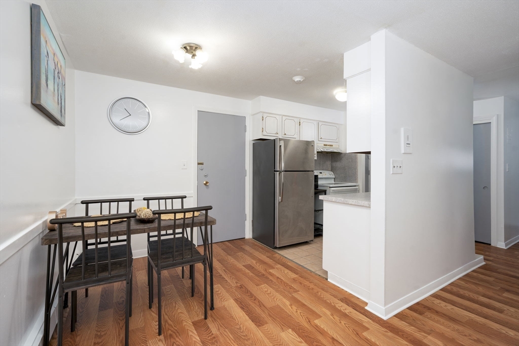426 Pleasant Street, Unit 17 Malden, MA 02148 - Photo 11 of 36 a kitchen with stainless steel appliances granite countertop a refrigerator a microwave a stove and a dining table with wooden floor
