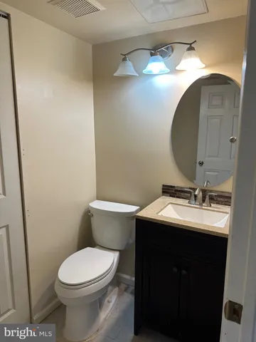 a bathroom with a toilet sink vanity and mirror