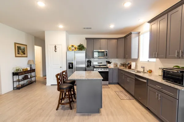 a kitchen with stainless steel appliances granite countertop a refrigerator a sink dishwasher a stove and white cabinets with wooden floor