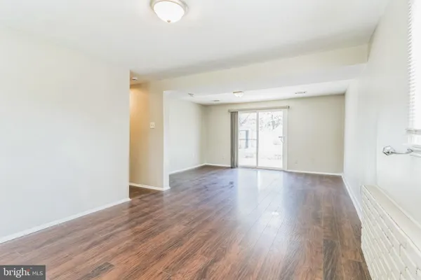 a view of an empty room with wooden floor and window