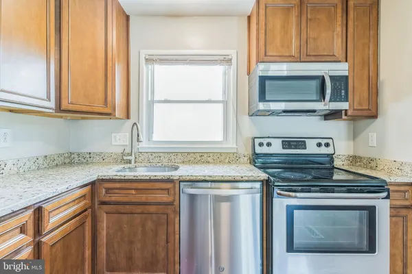 a kitchen with granite countertop cabinets stainless steel appliances and a sink