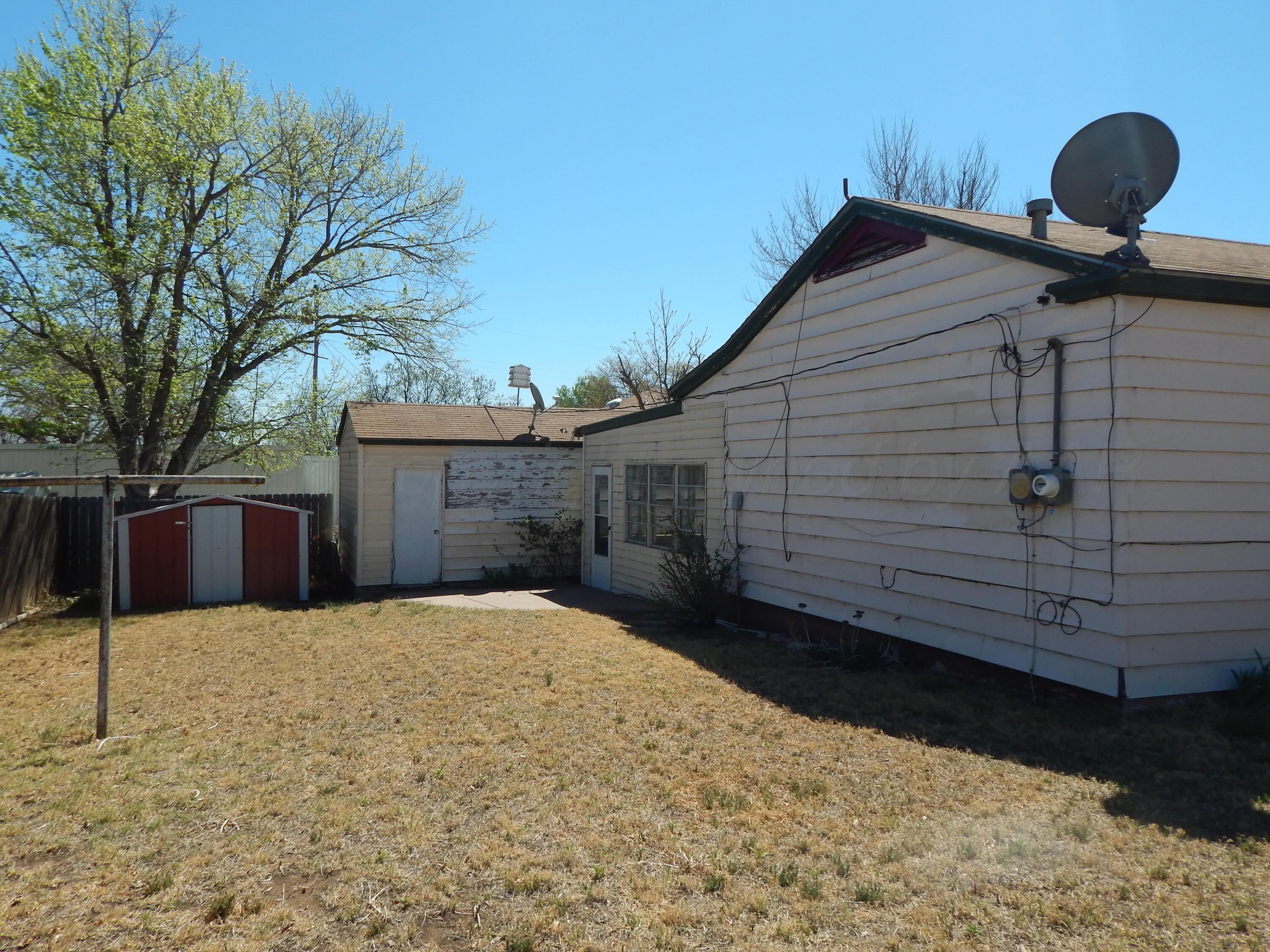 519 Third Street McLean, TX 79057 - Photo 18 of 19 a backyard of a house with large trees and wooden fence