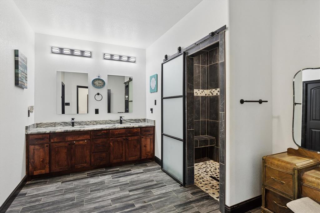 403 Polk Road Bowie, TX 76230 - Photo 16 of 36 Bathroom with a walk in shower, double vanity, and wood finished floors