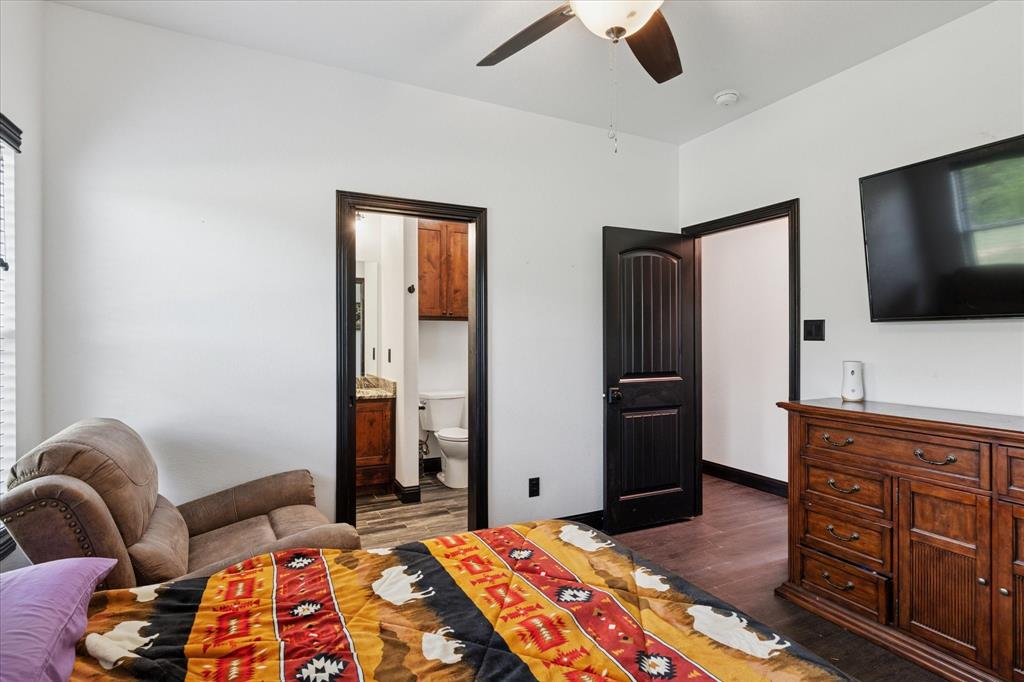403 Polk Road Bowie, TX 76230 - Photo 22 of 36 Bedroom with dark wood finished floors, connected bathroom, and ceiling fan