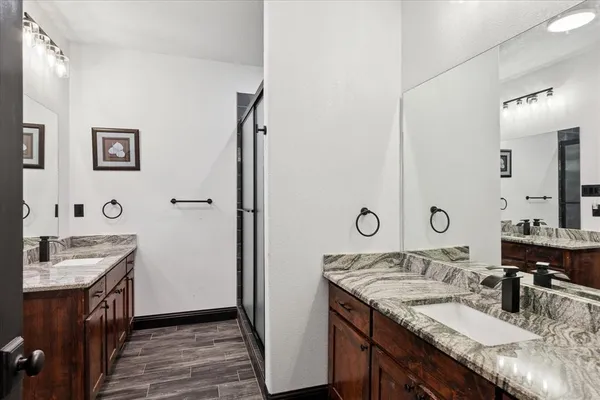 a bathroom with a granite countertop sink a mirror and shower