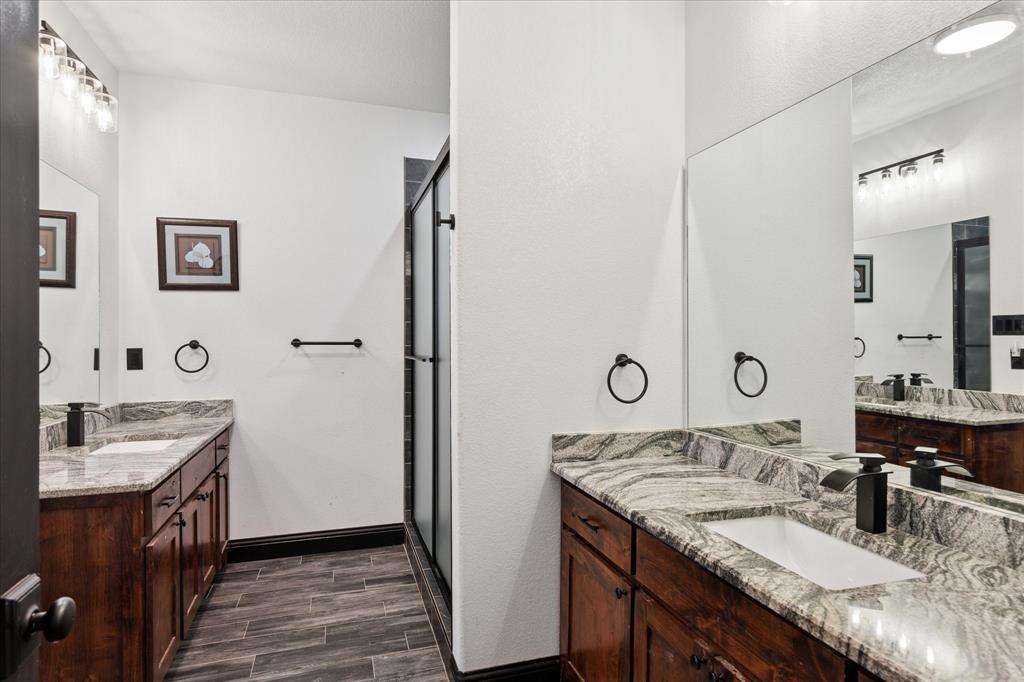 403 Polk Road Bowie, TX 76230 - Photo 23 of 36 Full bath with wood finished floors, two vanities, and a stall shower