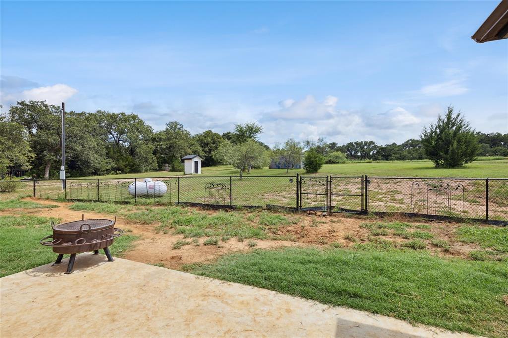 403 Polk Road Bowie, TX 76230 - Photo 28 of 36 View of yard featuring a patio, a shed, and a gate
