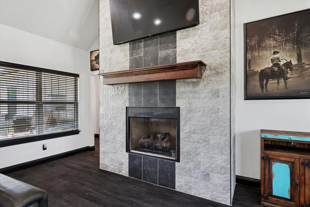 403 Polk Road Bowie, TX 76230 - Photo 5 of 36 Unfurnished living room with wood finished floors, vaulted ceiling, and a fireplace