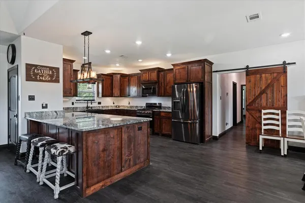a kitchen with kitchen island granite countertop a stove and a refrigerator