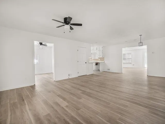 a view of empty room with wooden floor and ceiling fan