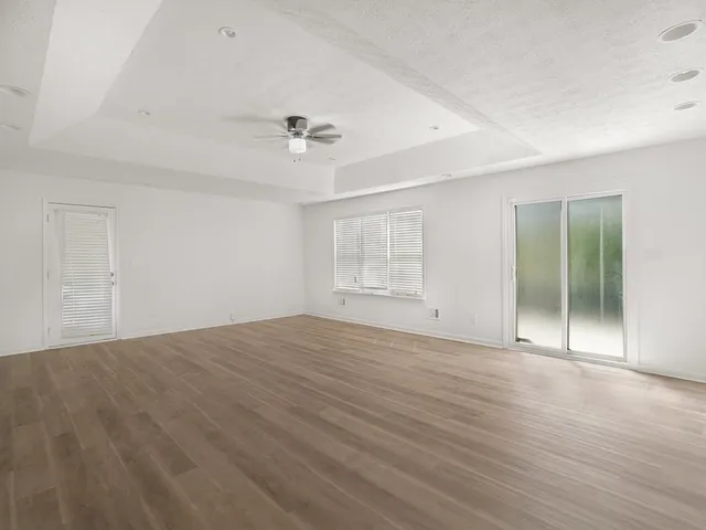 a view of an empty room with window and wooden floor