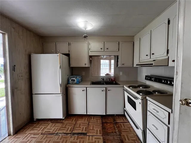 a kitchen with granite countertop a refrigerator stove and white cabinets