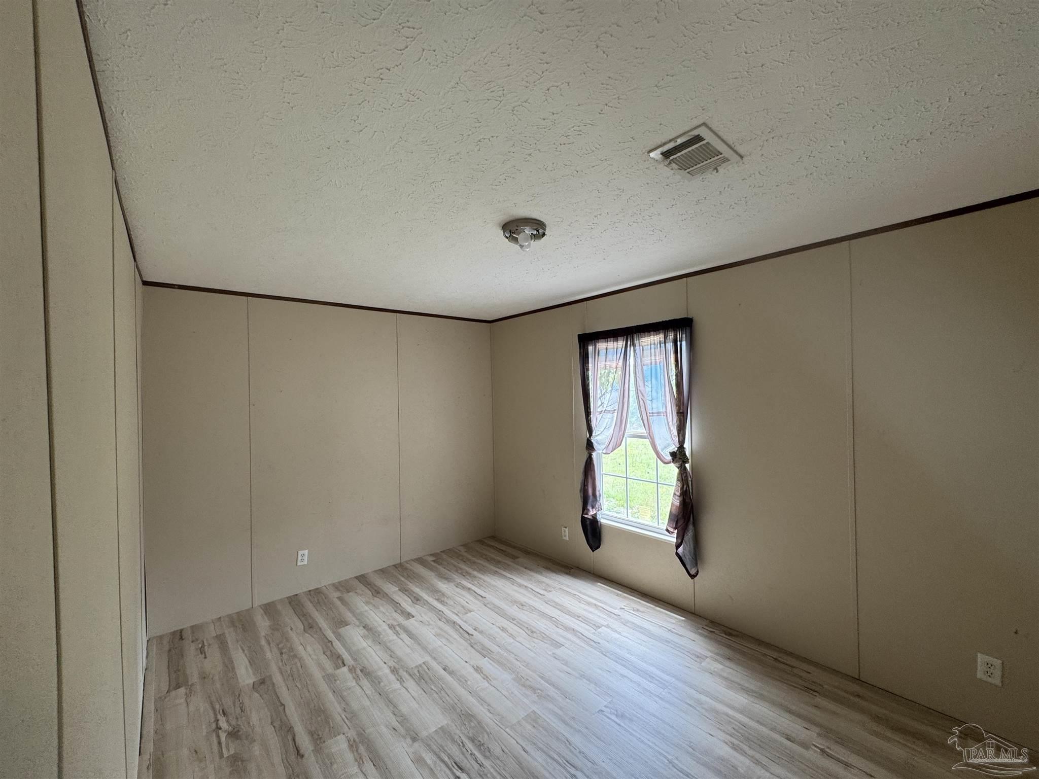 4508 Farm Life Road Milton, FL 32583 - Photo 13 of 20 an empty room with wooden floor and windows