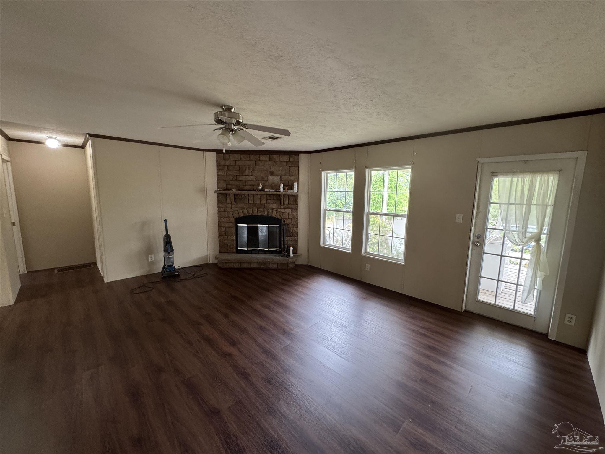 4508 Farm Life Road Milton, FL 32583 - Photo 2 of 20 an empty room with wooden floor fireplace and windows