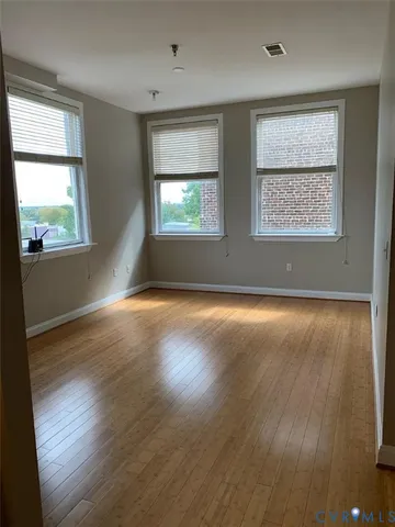 an empty room with wooden floor and windows