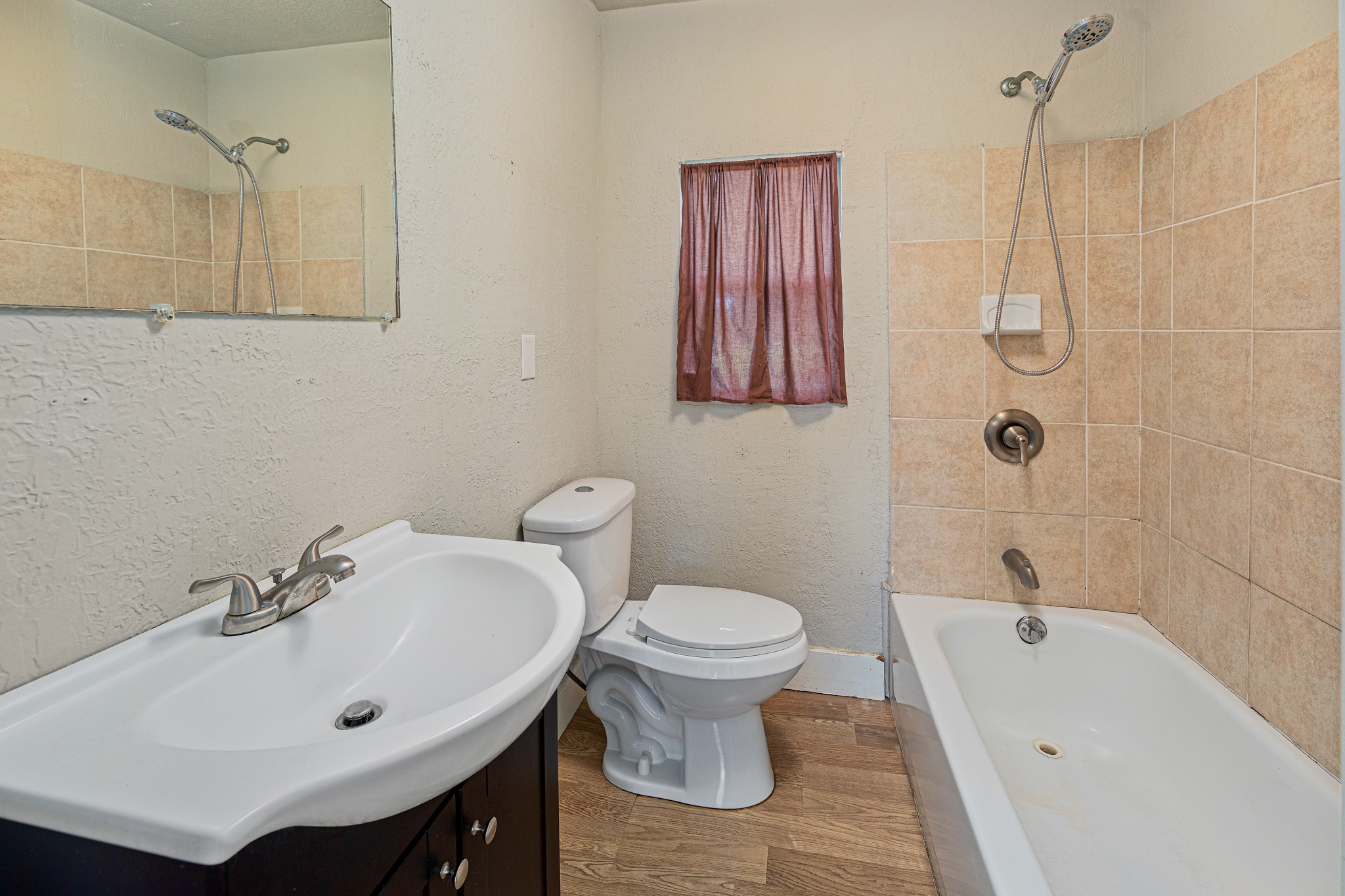 322 Blanco Avenue Luling, TX 78648 - Photo 11 of 20 A compact bathroom offers essential fixtures, a simple vanity, and a tiled shower-tub combination.