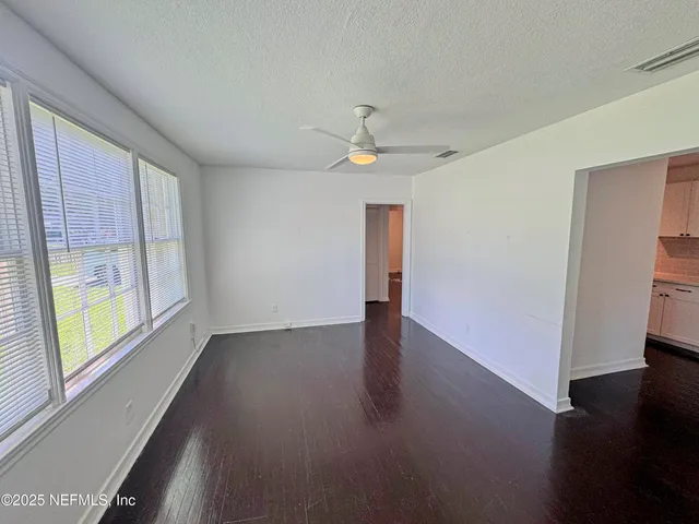 an empty room with wooden floor and windows