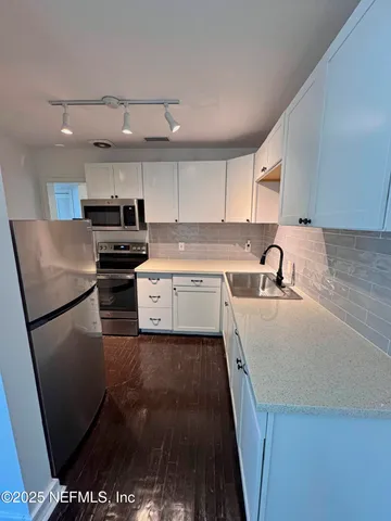 a kitchen with stainless steel appliances a sink a stove a refrigerator and cabinets