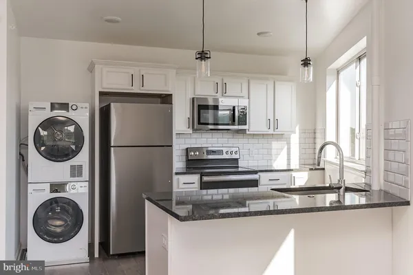 a kitchen with stainless steel appliances granite countertop a sink a stove a washer and dryer