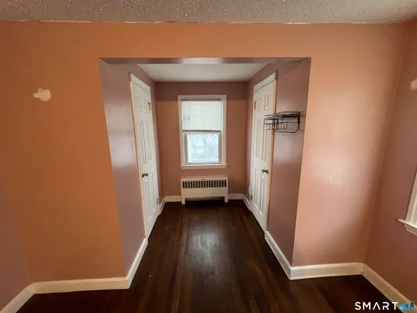 a view of a hallway with wooden floor and a bathroom