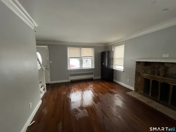 an empty room with wooden floor fireplace and windows
