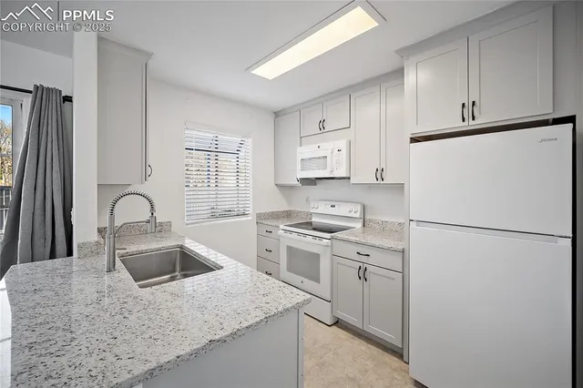 a kitchen with granite countertop a sink a stove and cabinets