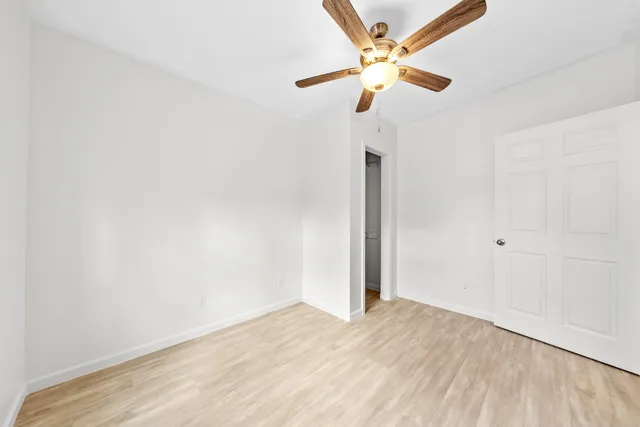 an empty room with a window and a ceiling fan