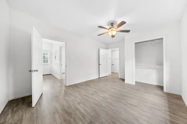 a view of a room with wooden floor and a ceiling fan