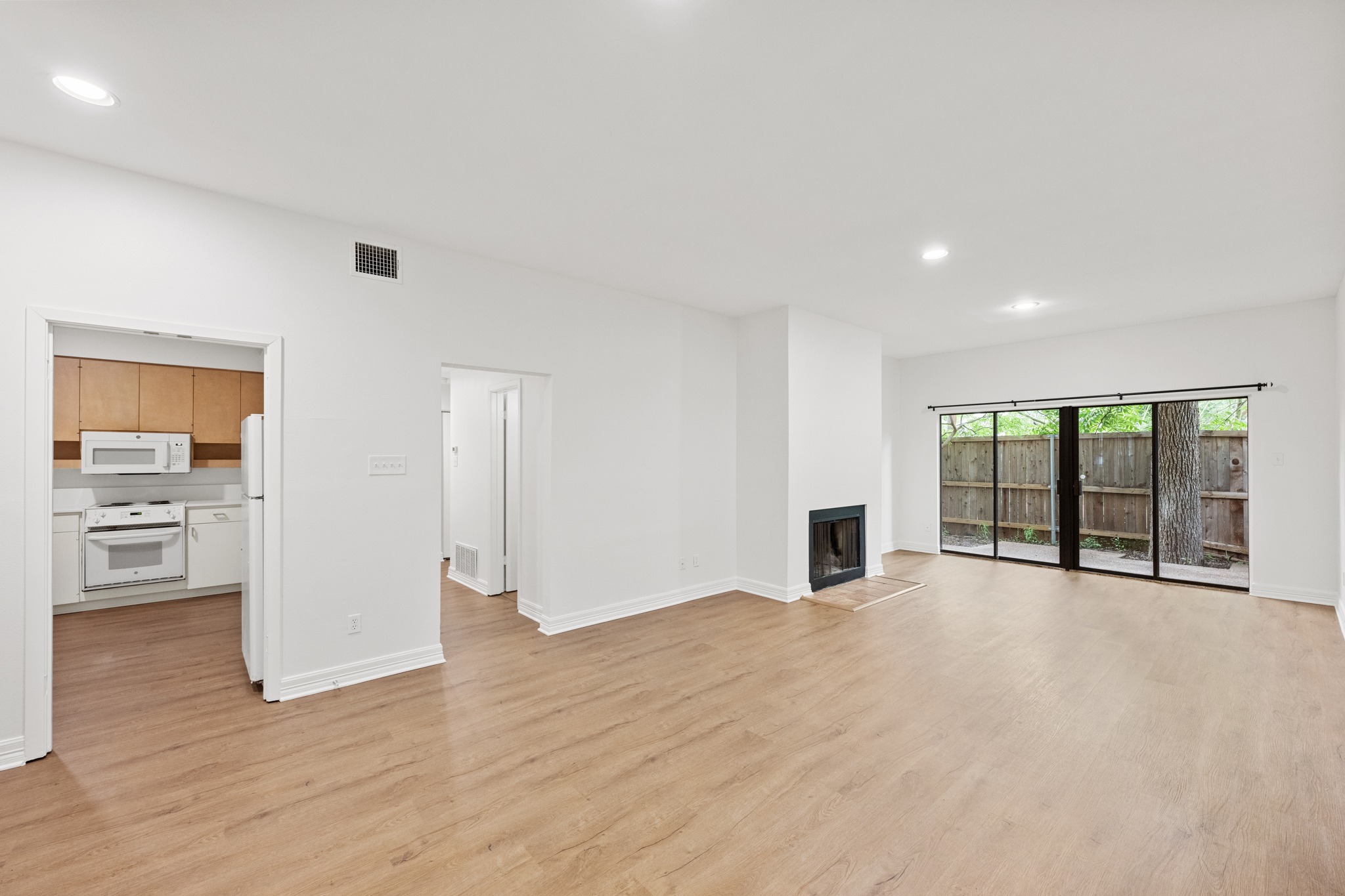 409 East 38th Street, Unit 101 Austin, TX 78705 - Photo 8 of 27 A well-lit living area with hardwood flooring connects seamlessly to the kitchen and offers direct access to outdoor greenery.