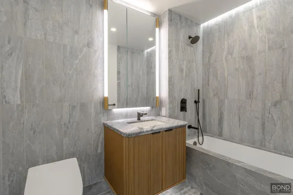 a bathroom with a granite countertop sink a toilet and shower