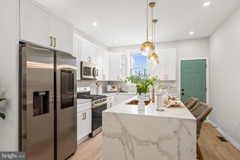 a kitchen with stainless steel appliances a stove a sink a microwave a refrigerator and cabinets