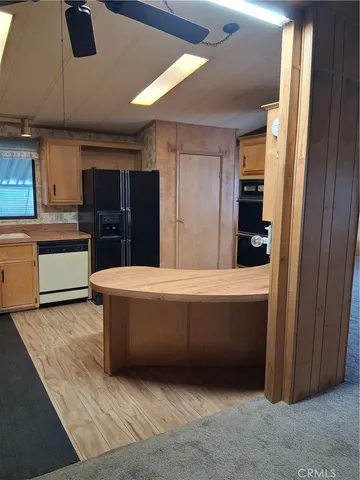 a living room with stainless steel appliances kitchen island granite countertop a refrigerator and a stove top oven