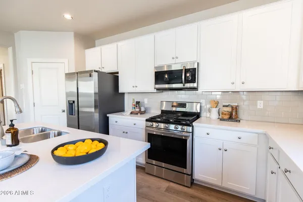 a kitchen with stainless steel appliances a stove a sink a refrigerator and white cabinets