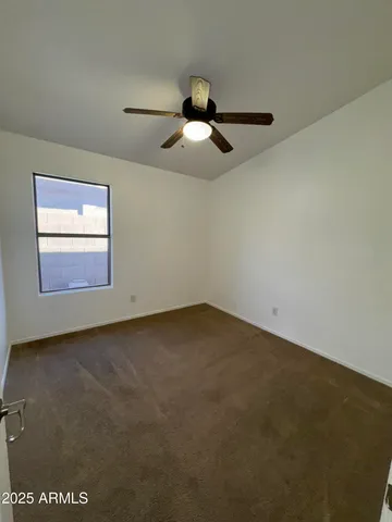 an empty room with a ceiling fan and window