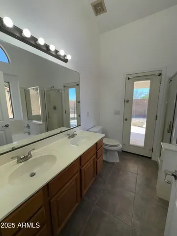 a spacious bathroom with a granite countertop sink a toilet mirror and a bathtub