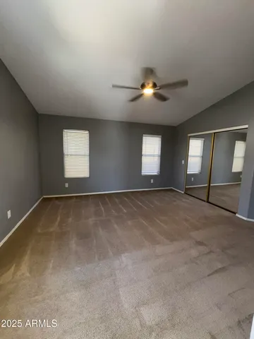 en empty room with windows and ceiling fan