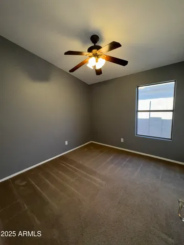 an empty room with windows and chandelier fan