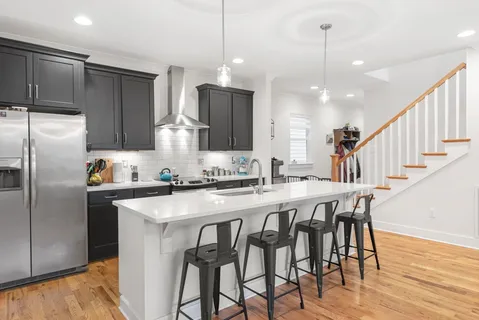 a kitchen with stainless steel appliances granite countertop a dining table chairs stove refrigerator and cabinets