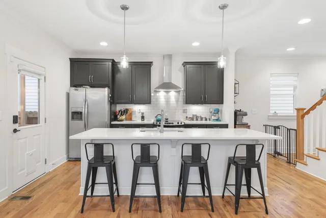a kitchen with stainless steel appliances kitchen island granite countertop a dining table chairs and wooden cabinets