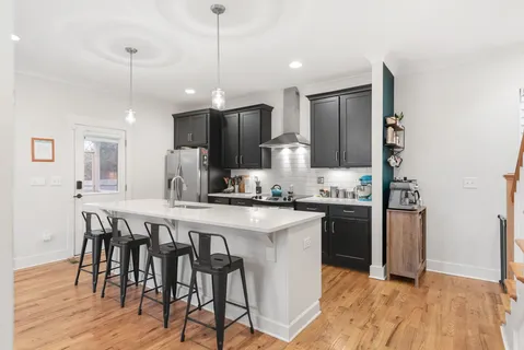 a kitchen with stainless steel appliances granite countertop a table chairs refrigerator and microwave