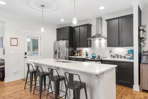 a kitchen with kitchen island granite countertop a table chairs sink and refrigerator