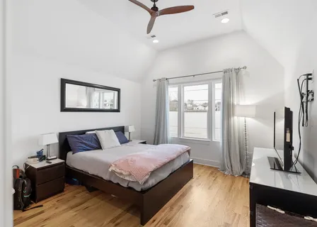 a bedroom with a bed wooden floor and window