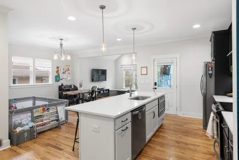 a large kitchen with stainless steel appliances kitchen island granite countertop a sink a counter space and a window