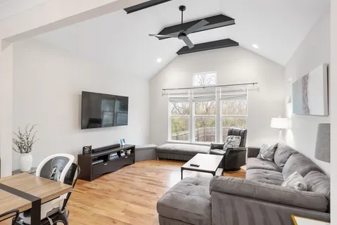 a living room with furniture a flat screen tv and a large window