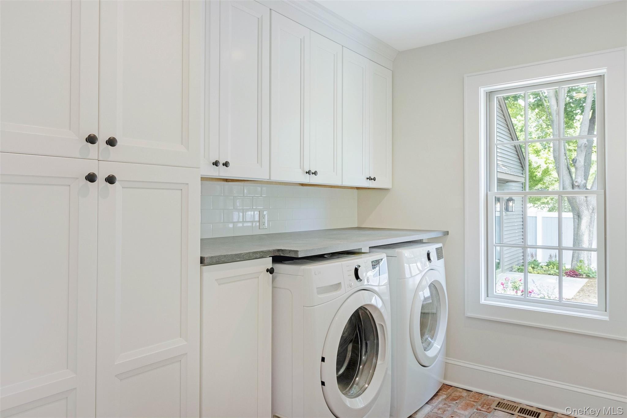 130 Sunset Lane Greenport, NY 11944 - Photo 11 of 34 Washroom with cabinet space, washer and clothes dryer, and brick patterned floors