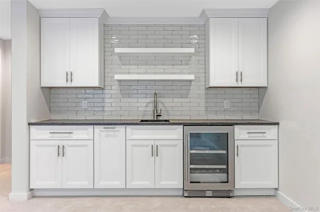 a view of kitchen with refrigerator and white cabinets