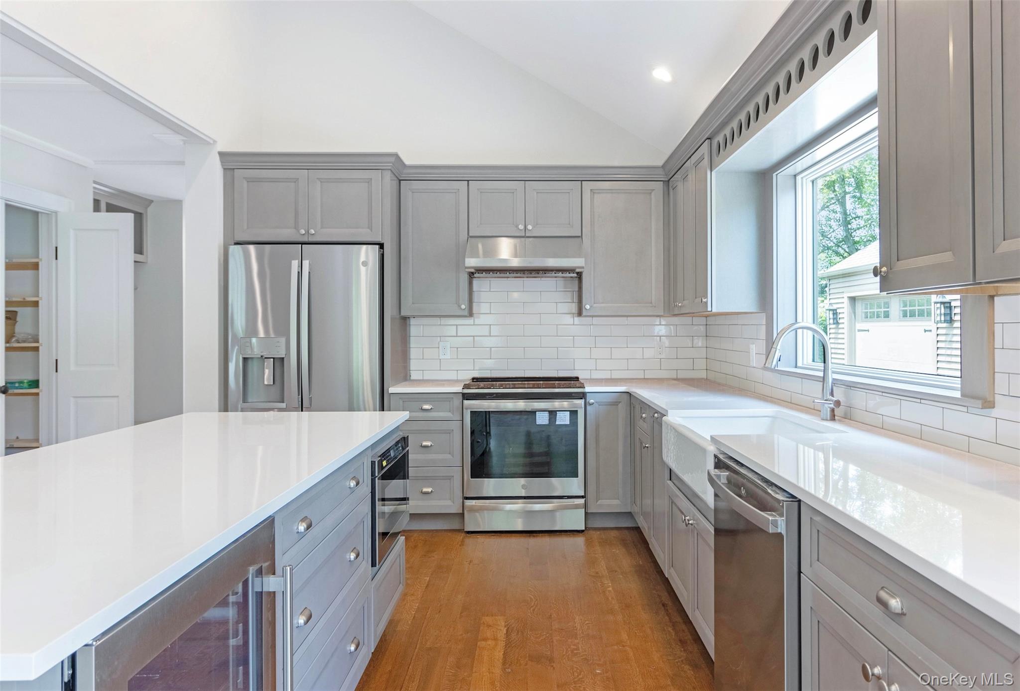 130 Sunset Lane Greenport, NY 11944 - Photo 7 of 34 Kitchen featuring gray cabinetry, wine cooler, appliances with stainless steel finishes, light wood-style floors, and backsplash